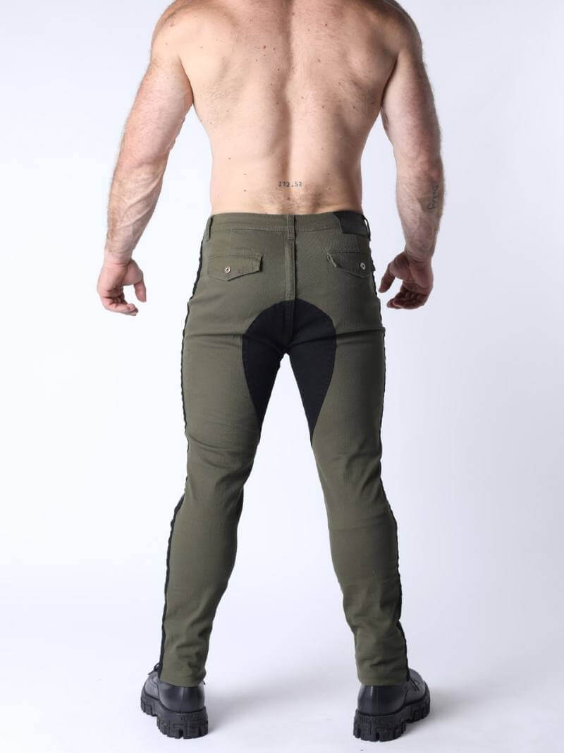 Person wearing green riding pants with black leather patches on a white background