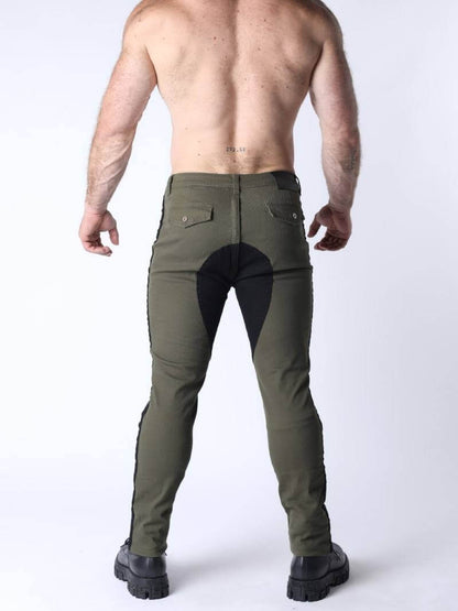 Person wearing green riding pants with black leather patches on a white background