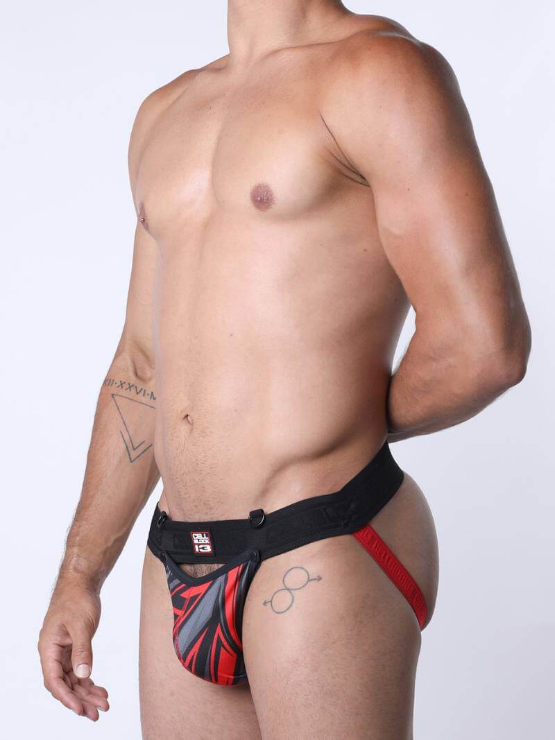 Man wearing a red and black patterned jockstrap on a white background